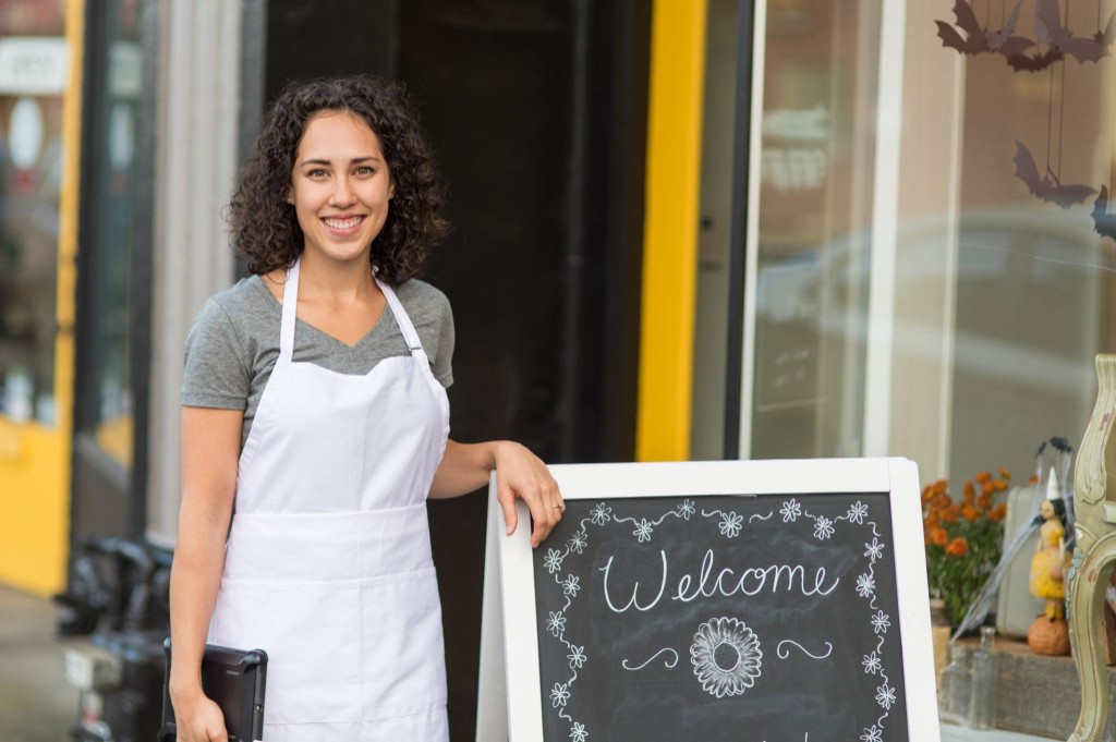 Small business owner welcoming customers at a local storefront