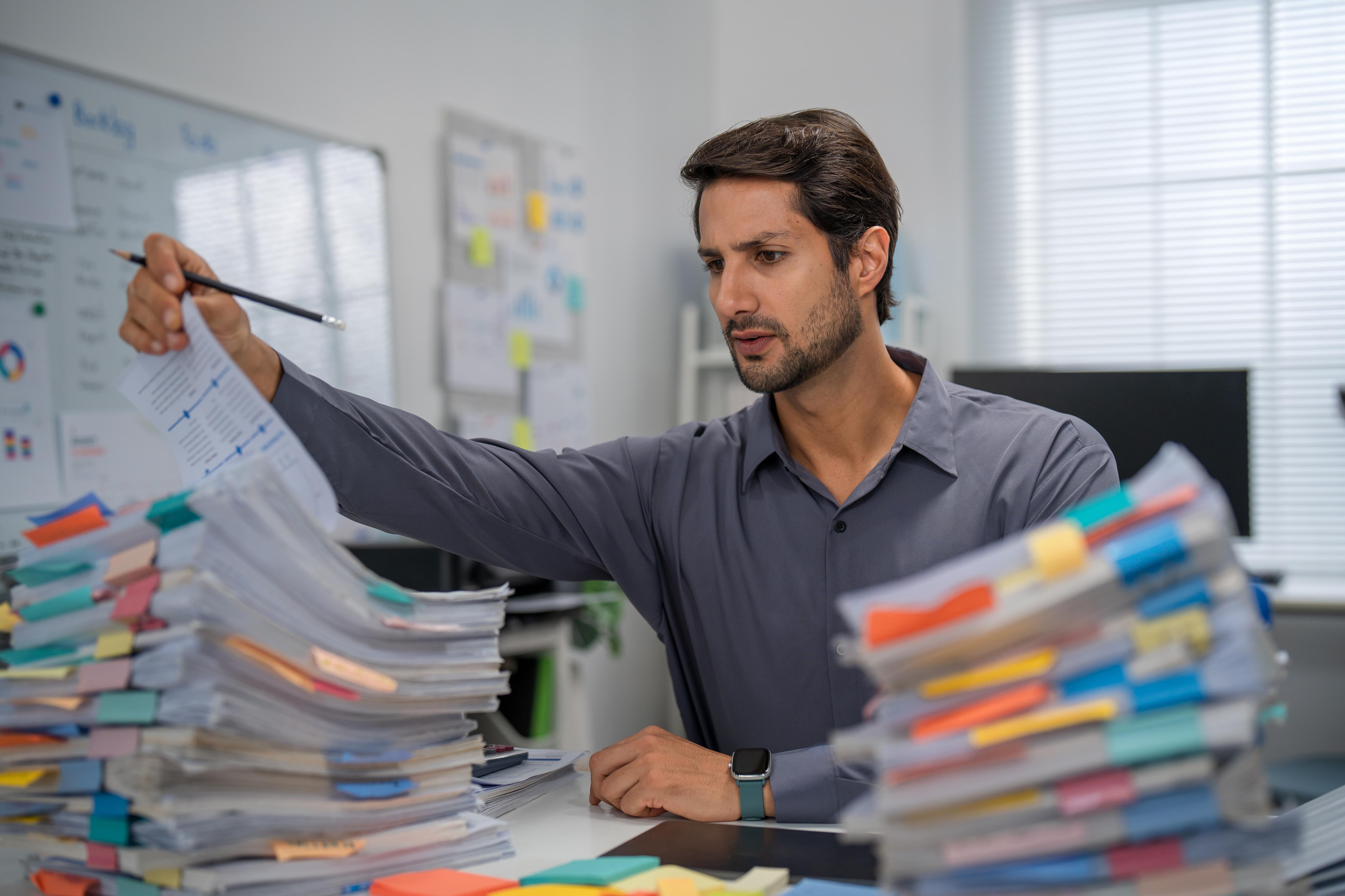 Procurement professional overwhelmed by stacks of paperwork and manual purchasing processes